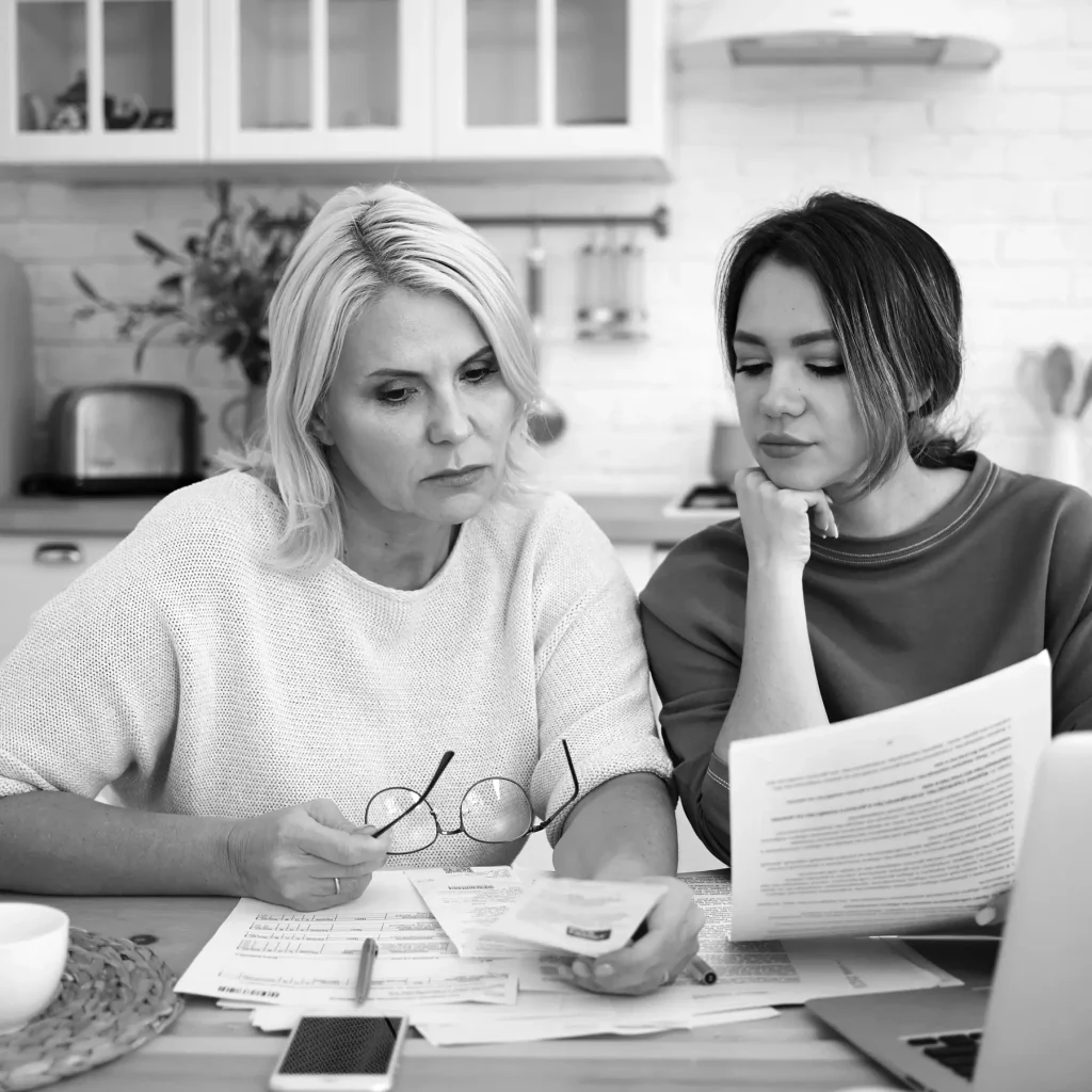 Erbe ausschlagen Notar Hebebrand Dortmund; Bild: zwei Frauen sitzen am Küchentisch und studieren Unterlagen, skeptischer Blick